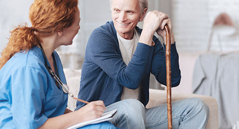 An older man sat with a nurse being visited at home